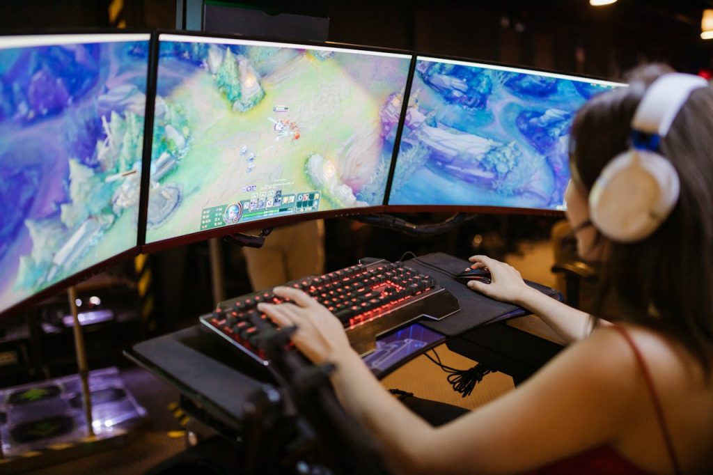 The Art of Drawing Readers In: Your attractive post title goes here A young woman intently gaming on a multi-screen setup, showcasing vibrant gaming visuals.